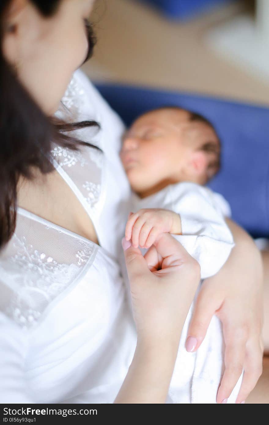 Young mother wearing white clothes holding newborn baby. Concept of motherhood and happiness.