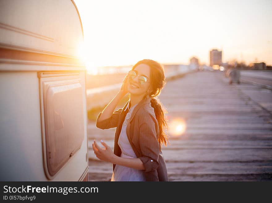 Beautiful young girl in sunglasses on the beach on a summer evening at sunset near trailer.n. Beautiful young girl in sunglasses on the beach on a summer evening at sunset near trailer.n