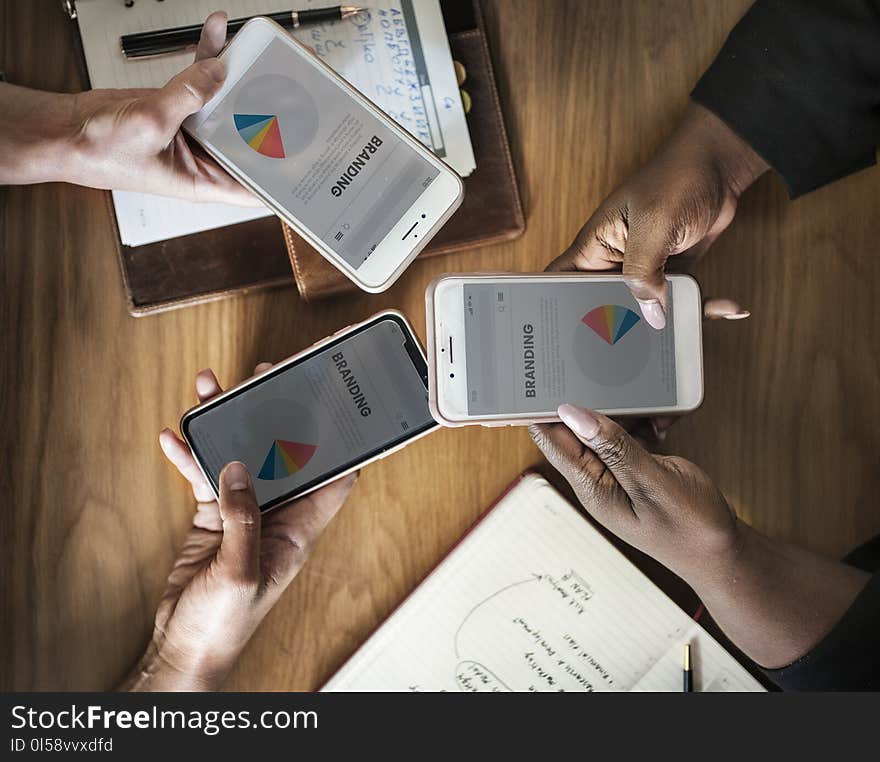 Three People Holding Phone Displaying Branding Pie Chart