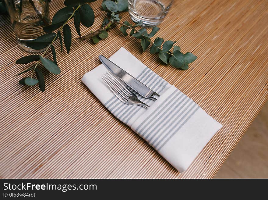 Silver Fork and Knife Inside Gray and White Table Napkin on Table