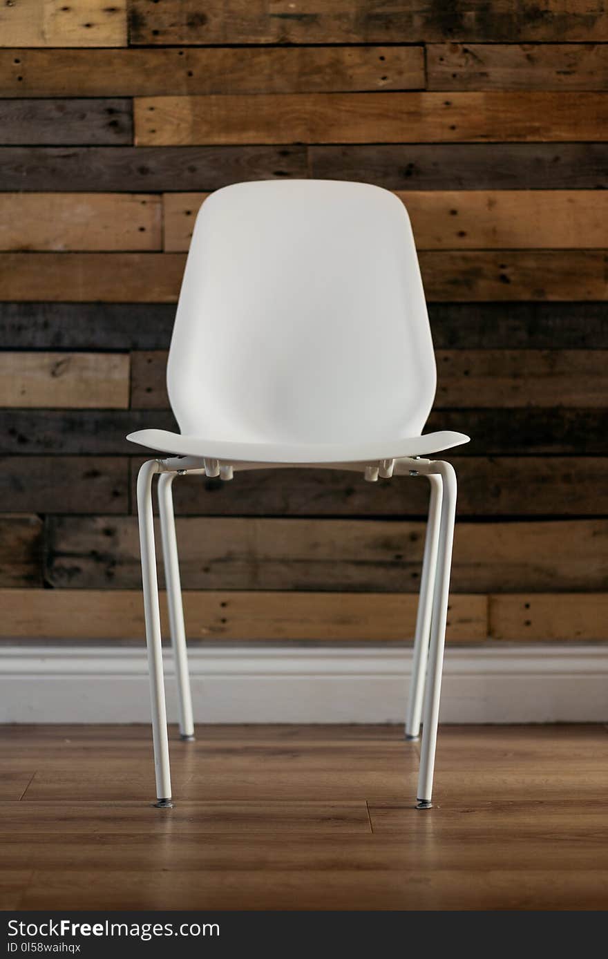 White Plastic Chair Beside Brown Wooden Wall in Home