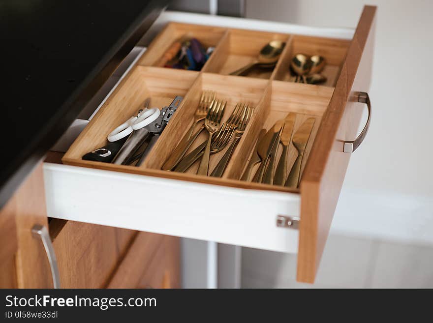 Silver-colored Cutlery Set on Brown Wooden Dresser