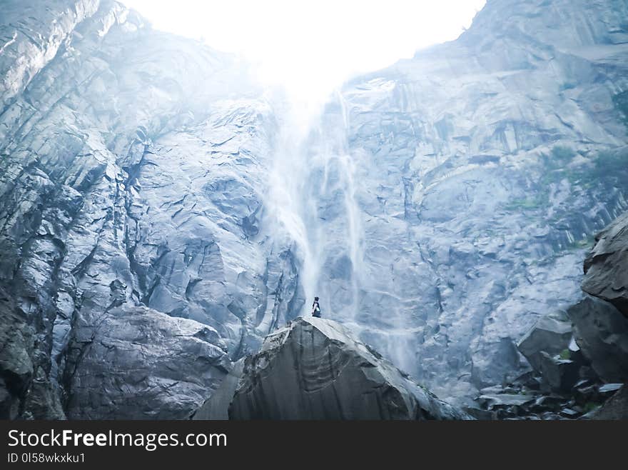 Low Angle Photography of Person Standing on Boulder Near Mountain