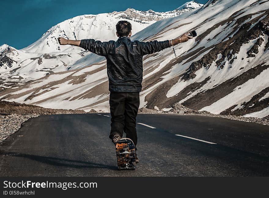 Photo of a Man I the Middle of Road Using Skateboard