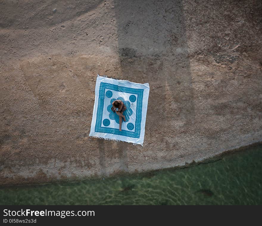 Photo of Person Sitting Near Body of Water