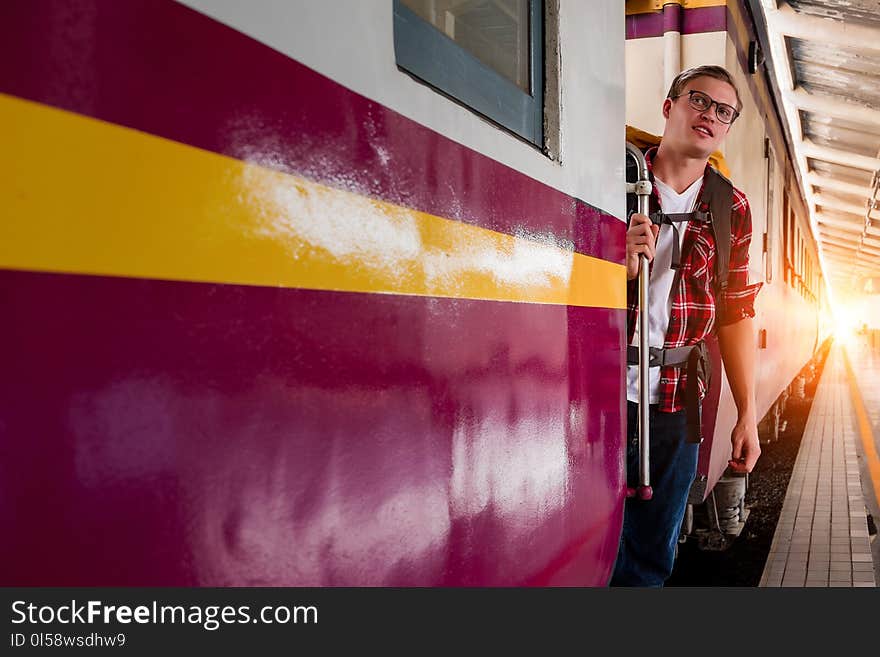 Man Wearing Red Button-up Shirt and Blue Jeans Holding Silver Train Side Rail