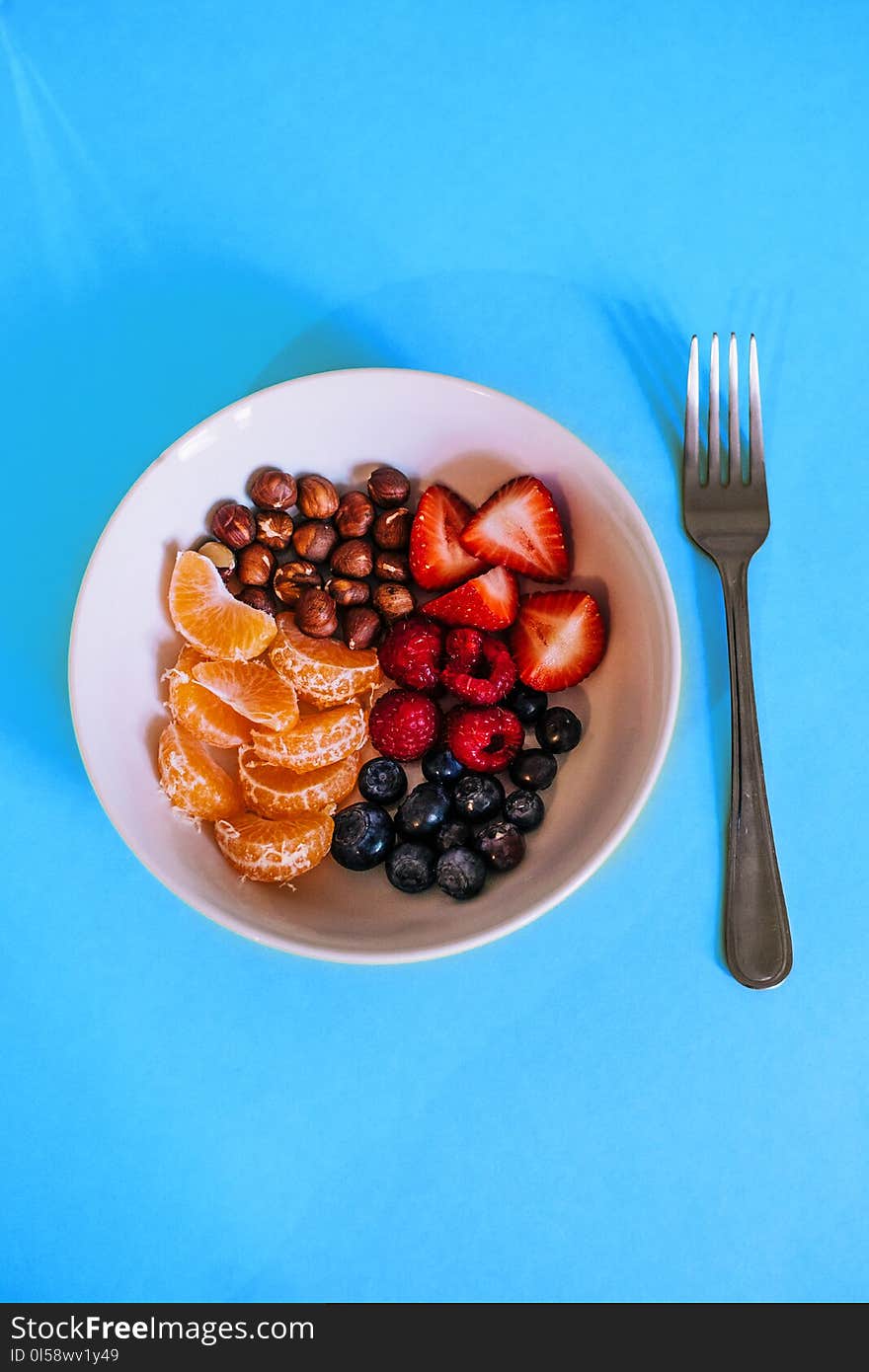 Variety of Fruits on White Ceramic Bowl With Gray Fork