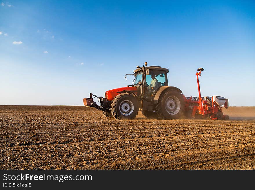 Farmer seeding, sowing crops at field.