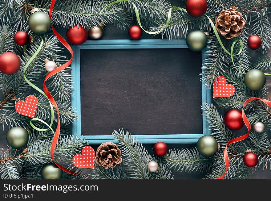 Christmas frame in green and red, top view with text space. Fir twig decorated with baubles, hearts and stars. Christmas frame in green and red, top view with text space. Fir twig decorated with baubles, hearts and stars