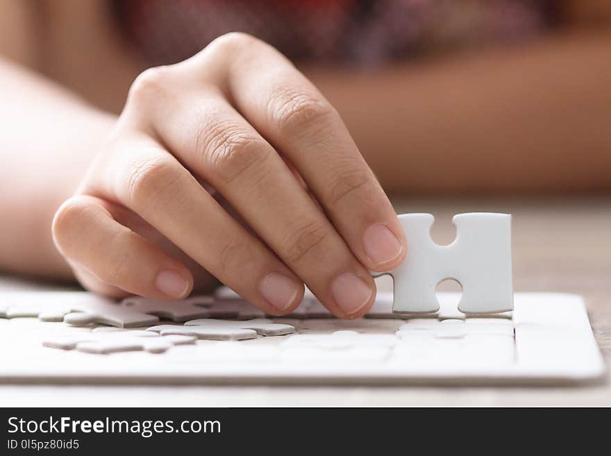 Close up shot hands of woman holding paper jigsaw puzzle select focus shallow depth of field