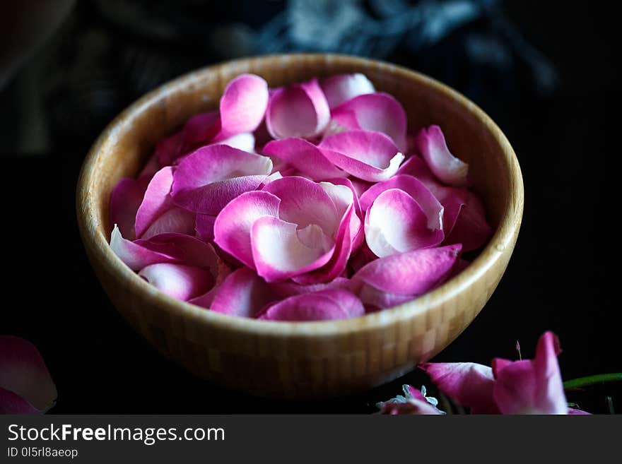 Close-up macro photo of fresh rose petals in a wooden bowl