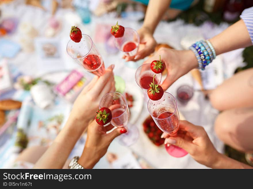 Hands with glasses cheers on summer day at picnic