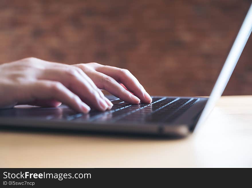 Closeup image of hands working and typing on laptop keyboard in office