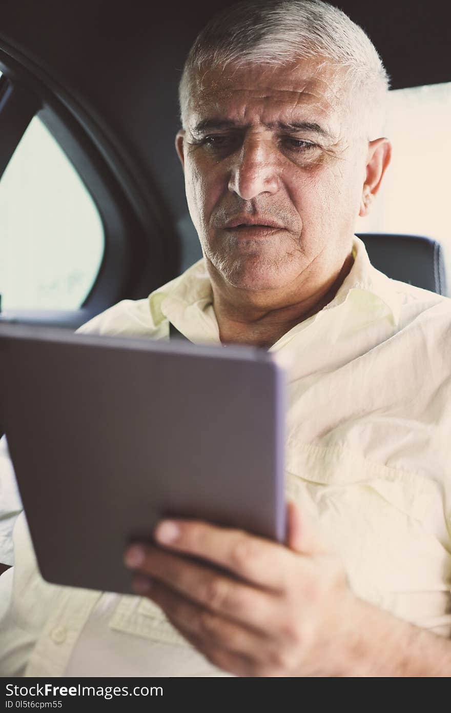 Business man using digital tablet and reading document. Senior man working in taxi. Business man using digital tablet and reading document. Senior man working in taxi.