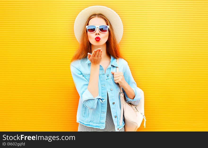 Stylish cool girl sends an air kiss on orange background