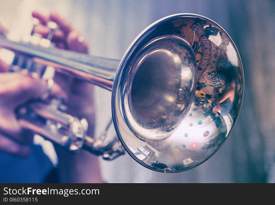 The trumpeter is playing on a silver trumpet. Trumpet player