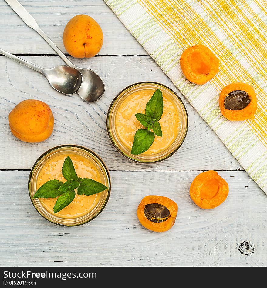 Smoothies of mulberries, apricot and mint in glass jars on white wooden background