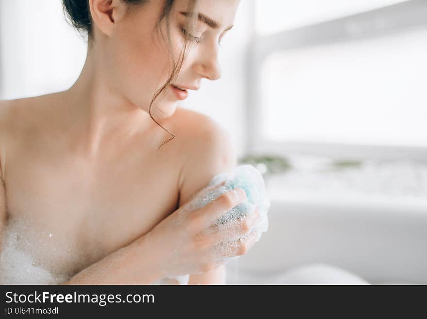 Female person soaps the body with a sponge