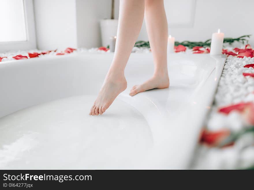 Woman in white bathrobe dips legs into the bath