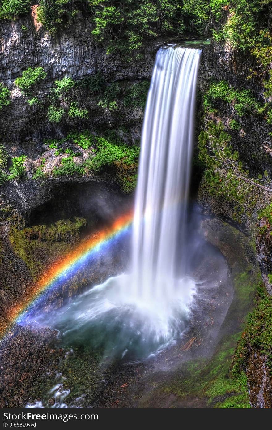 Rainbow over waterfalls in sunny day.