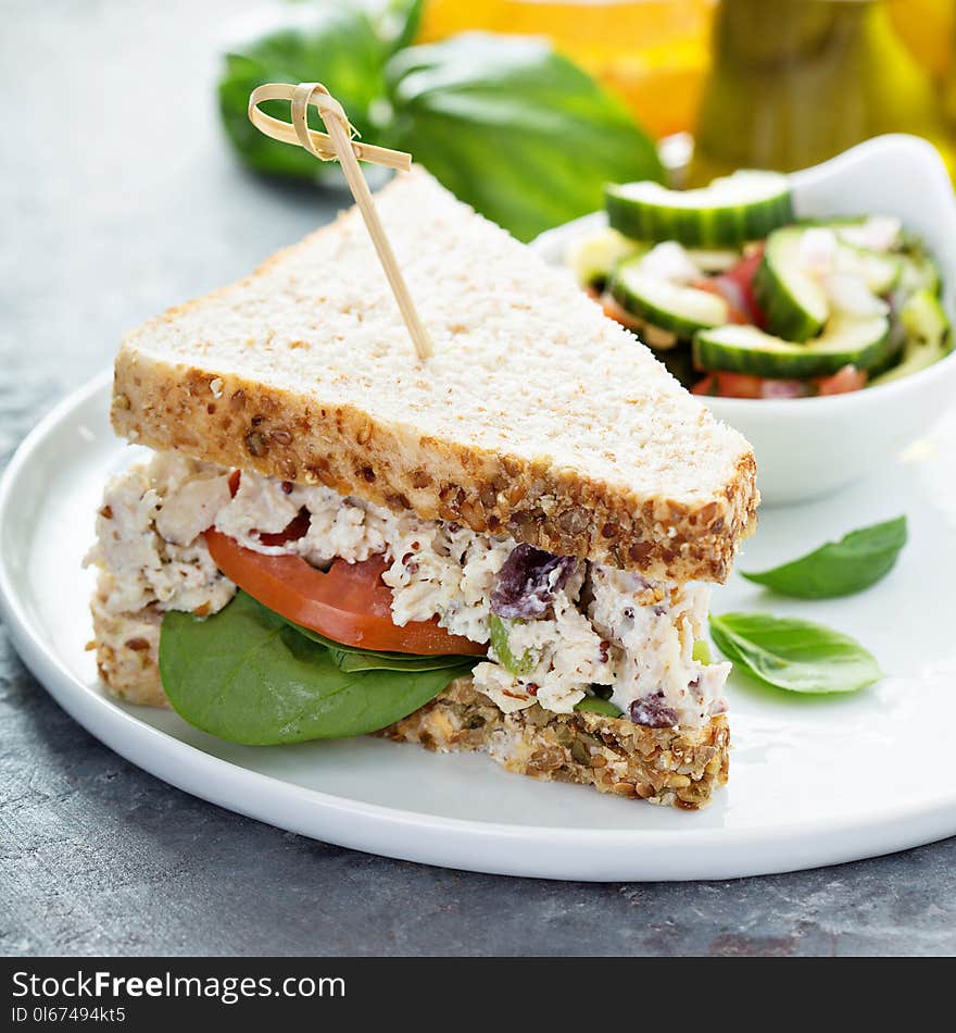 Chicken salad sandwich with spinach and tomato served with vegetable salad