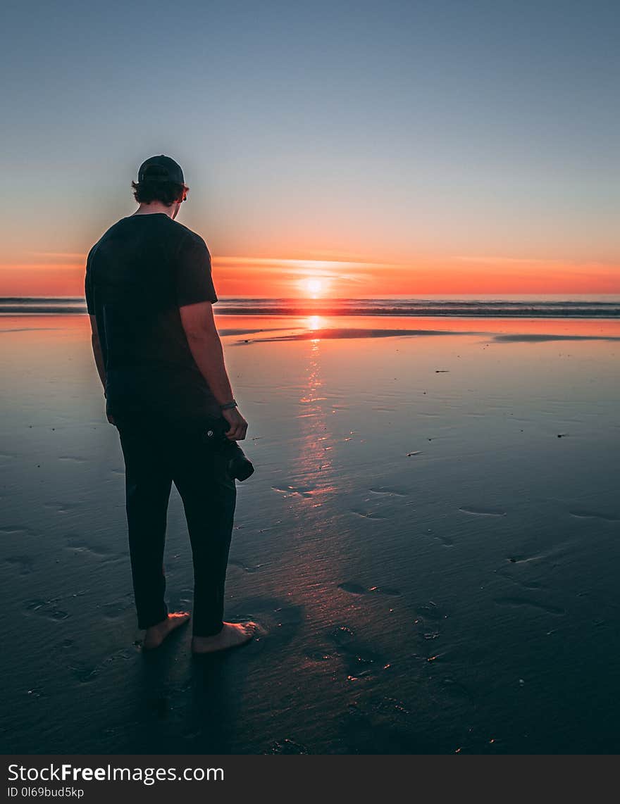 Man Standing on Beach during Sunset