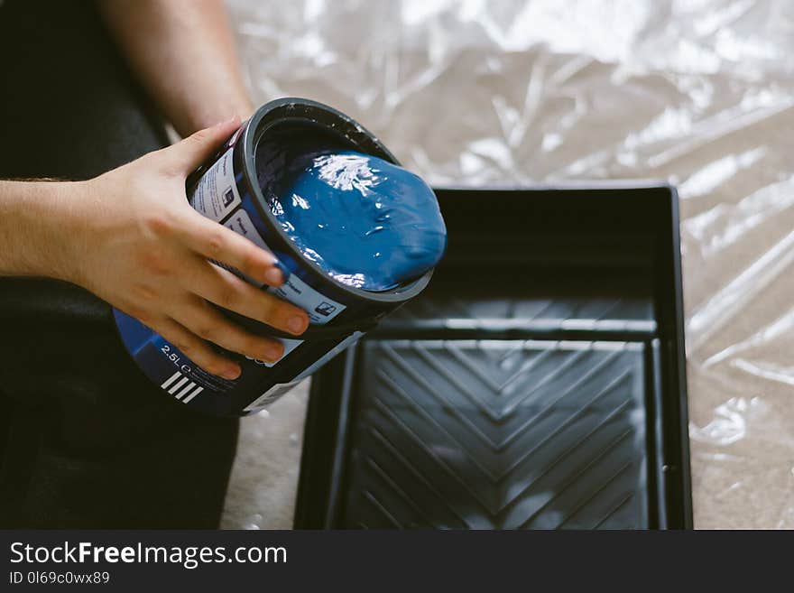 Person Holding Can of Blue Paint