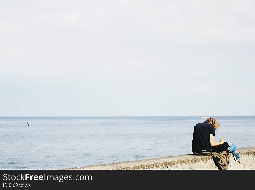 Person Wearing Black Shirt Sitting on Gray Surface