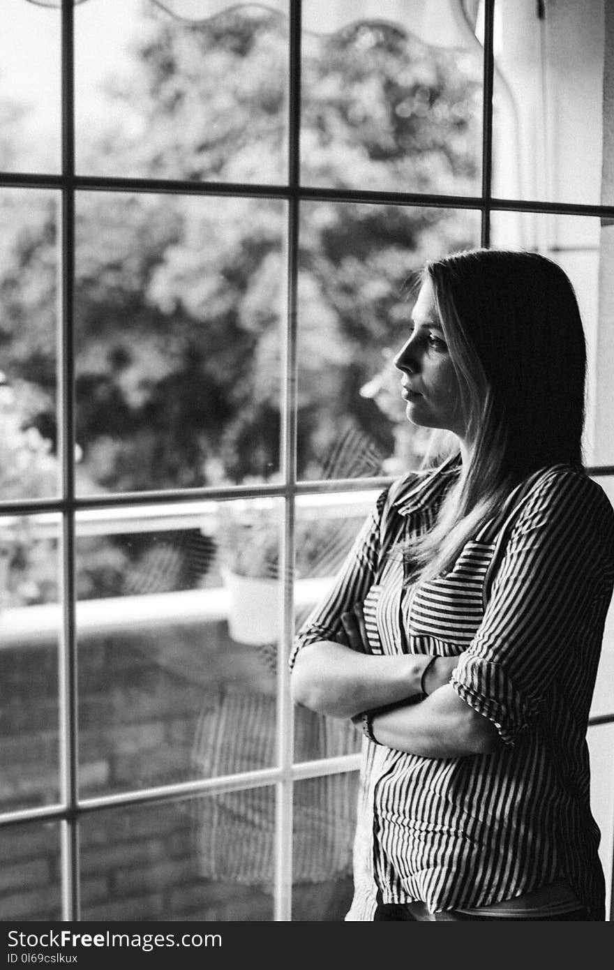 Grayscale Photo of Woman Standing Beside Mirror