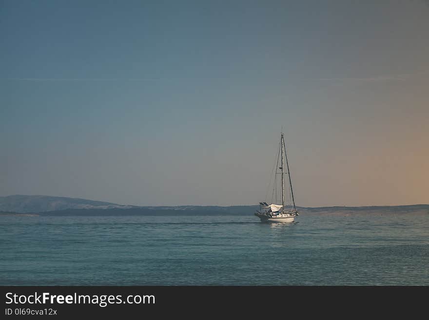 White Sailboat on Body of Water Under White Sky