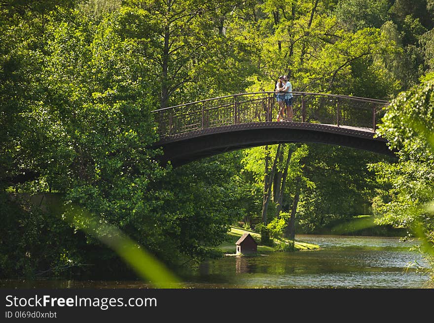 Photo of Couple Hugging on Bridge over River