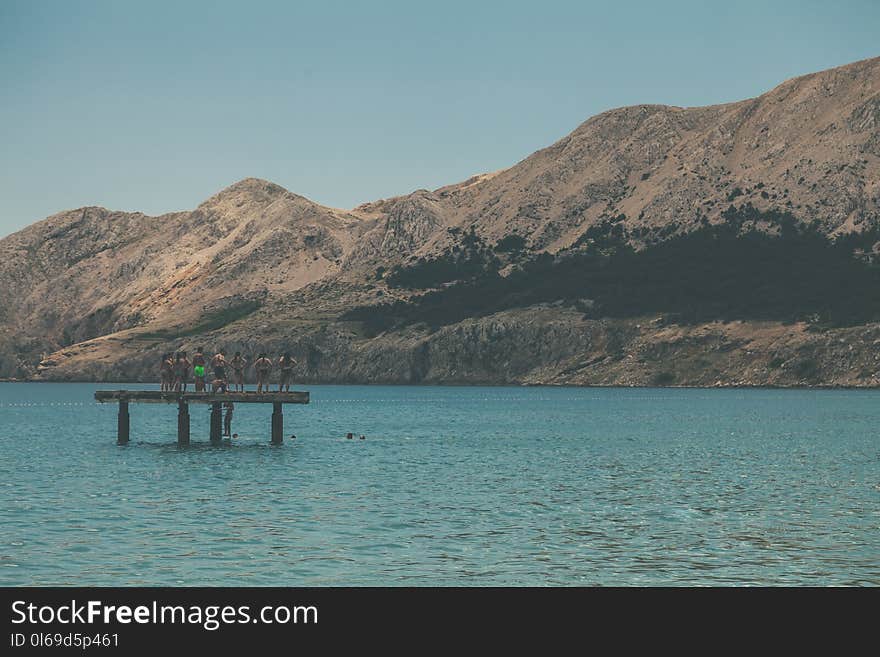 People Standing on Terrace in Middle of Body of Water Within Mountain Range