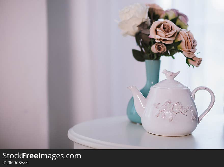 White Ceramic Teapot Near Flower Arrangement on White Surface