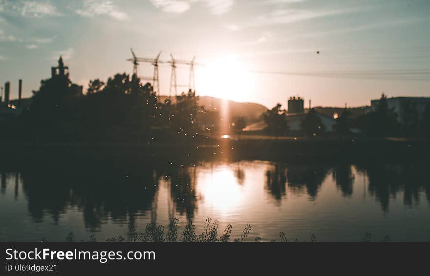 Silhouette of Building and Trees Near Body of Water during Golden Hour