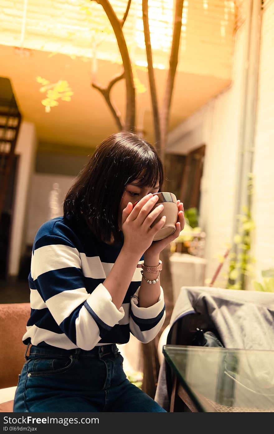 Woman Seated Outside Drinking from a Brown Bowl