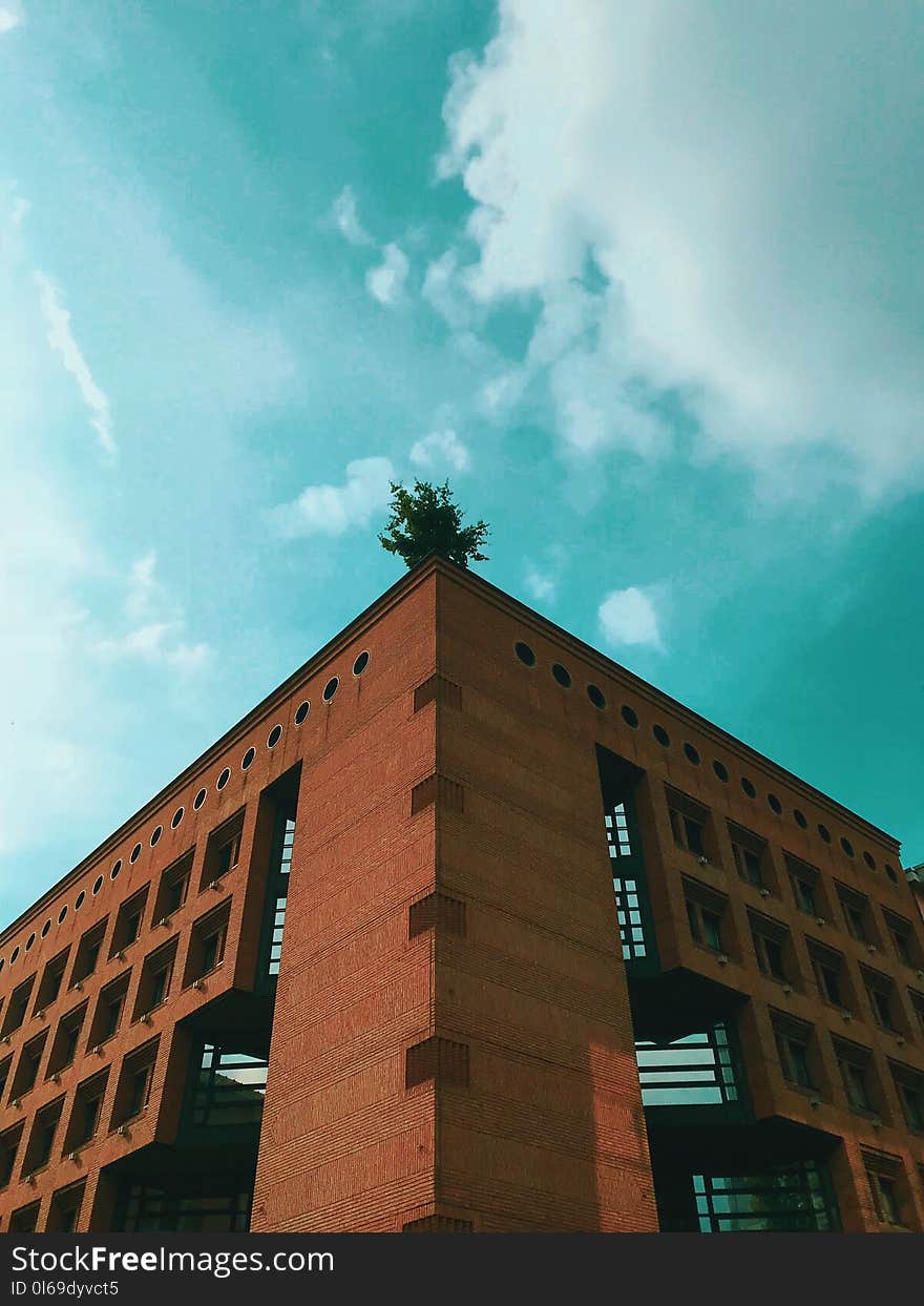 Brown Concrete Building Under Teal and White Cloudy Sky at Daytime