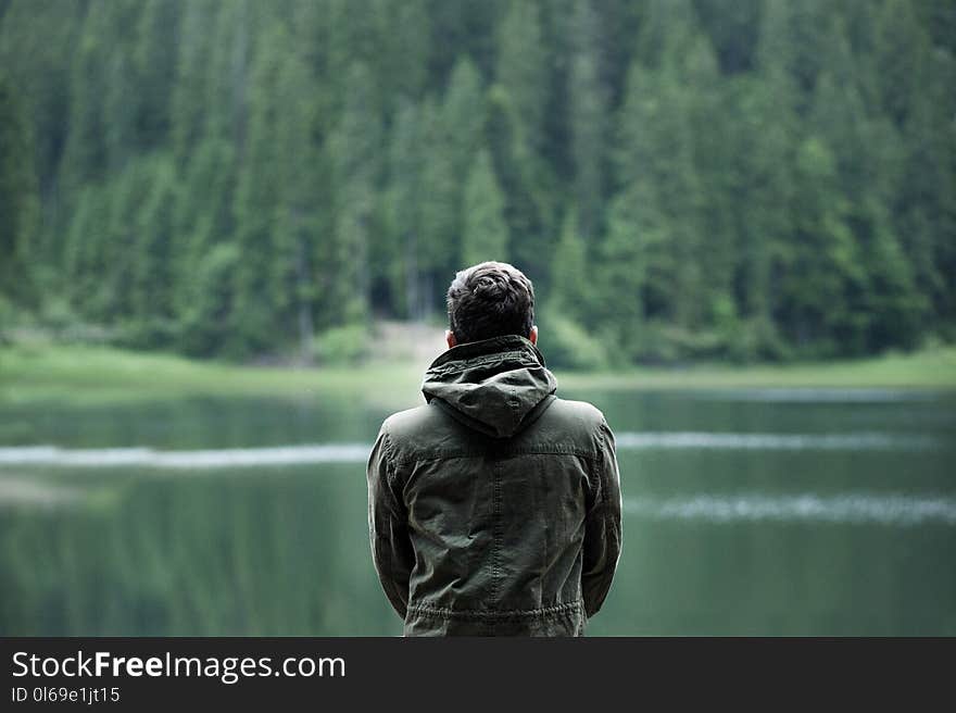 Photo of Man Wearing Hooded Jacket in Front of Body of Water