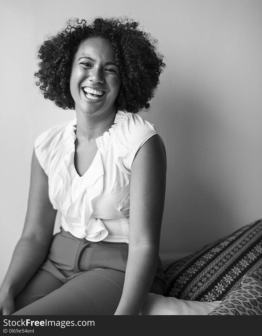 Gray scale Photograph of Woman Smiling Beside White Wall