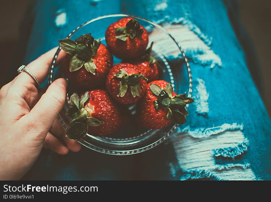 Person Holding Clear Glass Bowl of Strawberries