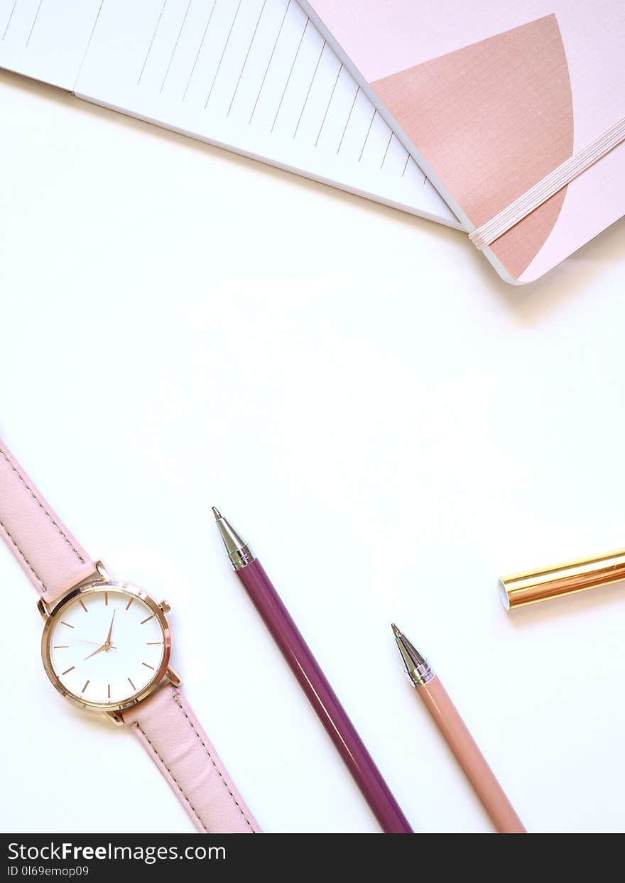 Flat lay Photography of Watch Near Pens and Notebook