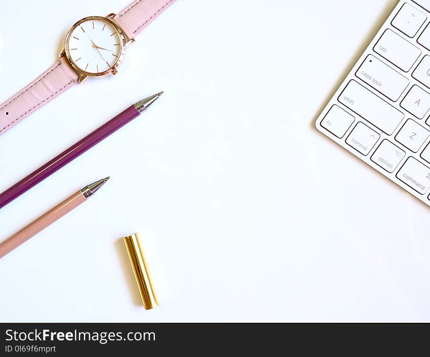 Round Gold-colored Watch and Two Pens