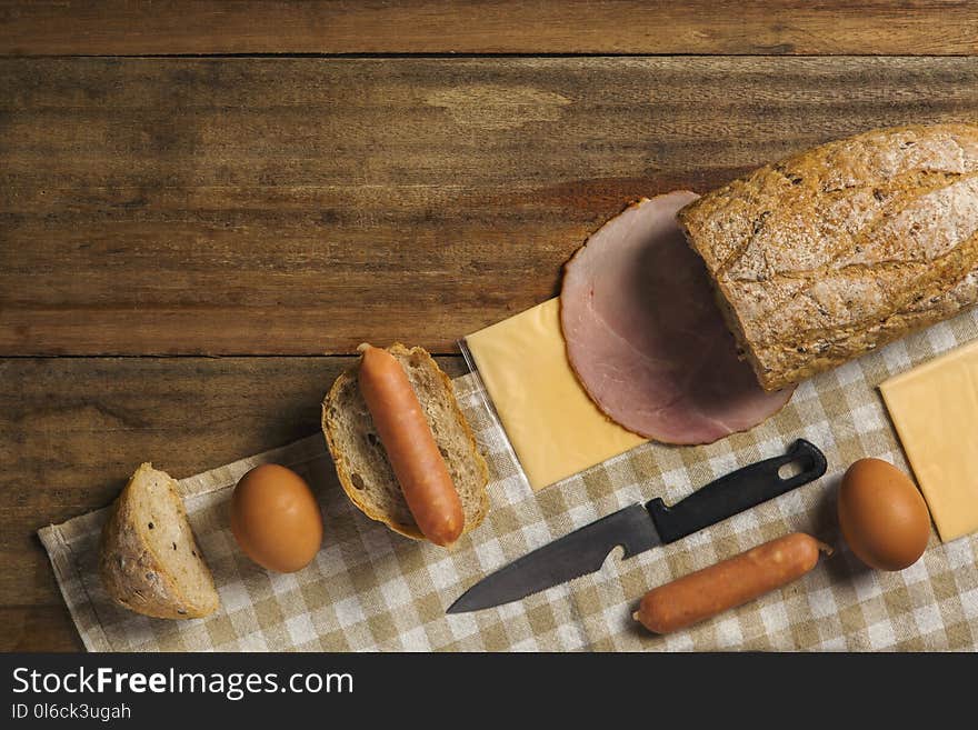 Flat lay of various ingredients for breakfast on wood background, bread, egg, sausage, ham, and cheese