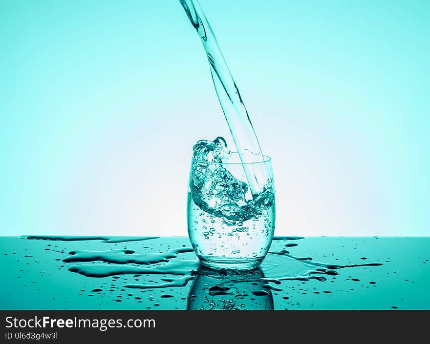 Creative splashing water in the glass on blue background.