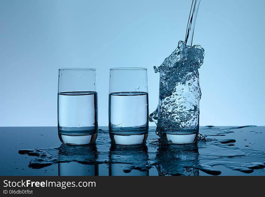 Creative splashing water in the glass on blue background.