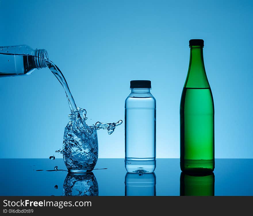 Creative splashing water in the glass on blue background.