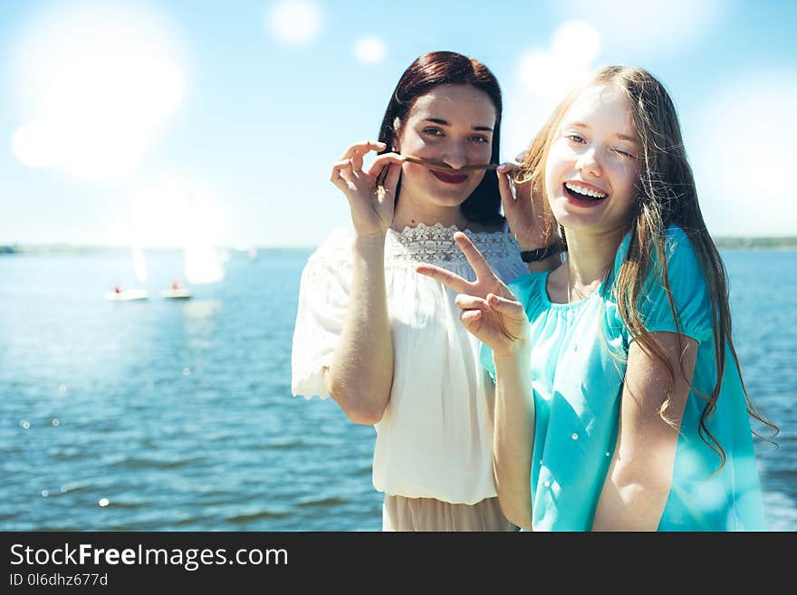 Two beautiful and cheerful girls on the background of the sea and sailing boats. Two beautiful and cheerful girls on the background of the sea and sailing boats.