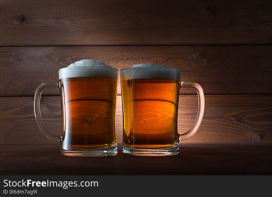 Two glasses of golden beer on wooden background