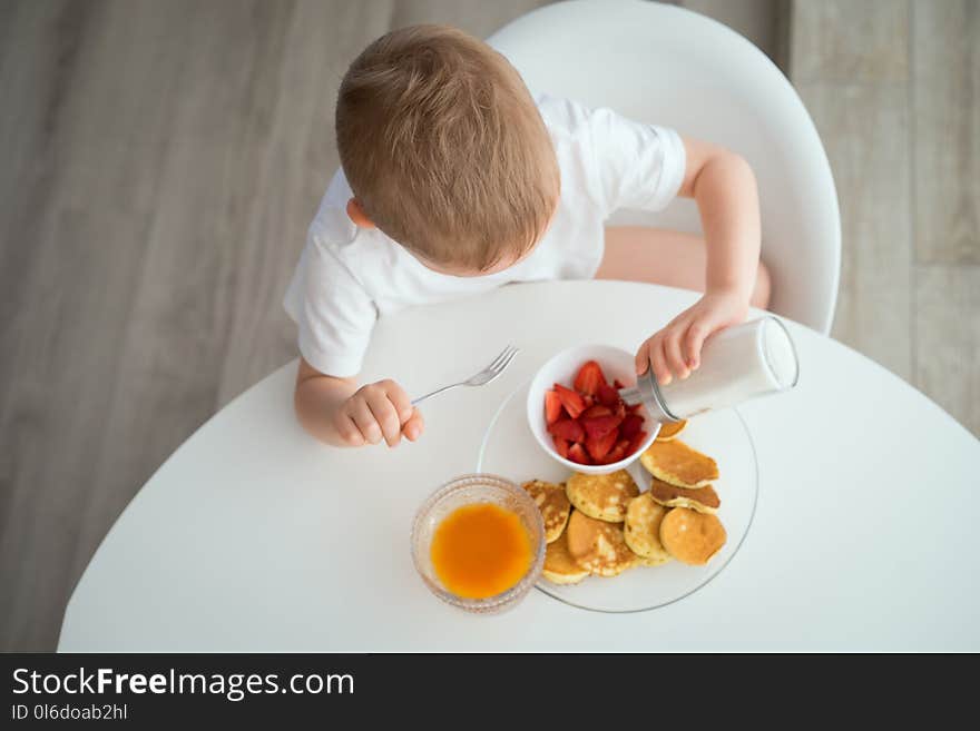 The child has Breakfast on a Sunny morning at white kitchen