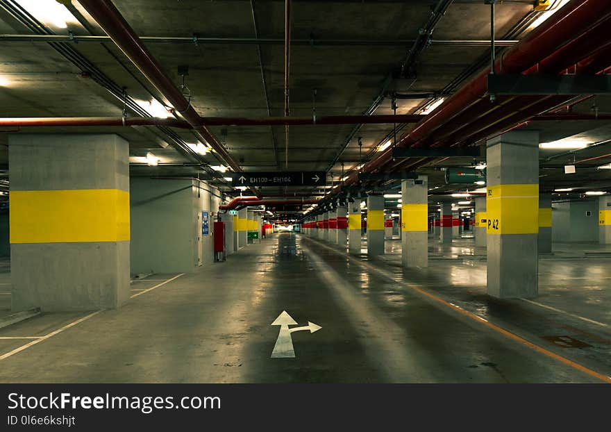 Perspective view of empty indoor car parking lot at the mall. Underground concrete parking garage with open lamp at night. White direction sign. Choose way to live your life. Wiring and plumbing.