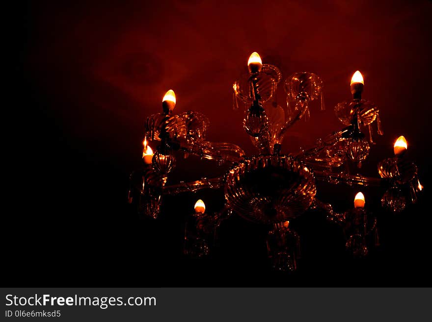 Luxury glass chandelier mounted on ceilings of the room. Red warm light from chandelier reflection on the wall